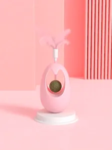 Detail view of pink catnip ball tumbler cat toy with feather wand on pink background