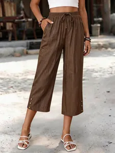 Model trägt braune, weite verkürzte Tencel-Hose mit Tasche und Knöpfen im Freien