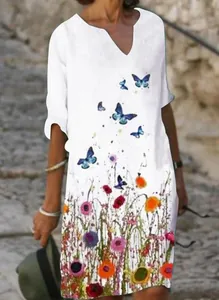 Detailed close-up showing colorful floral and butterfly prints on a white linen dress.