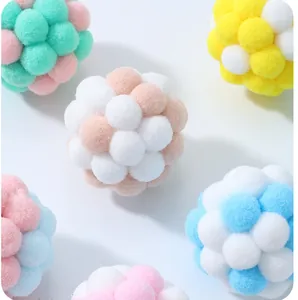 Macro detail of soft macaron colored plush pom-pom balls for interactive cat pet toys.
