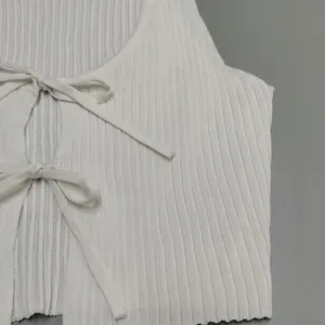 Detail shot of a white ribbed knit crop top featuring elegant tie-front bow design.