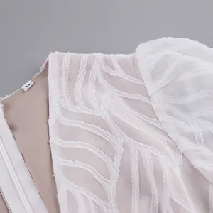 Detailansicht der weißen Blatt-Jacquard-Struktur mit einem M-Größenetikett am Kleid
