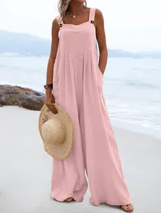 Detalle de un mono rosa sin mangas de pierna ancha con botones decorativos en la playa.