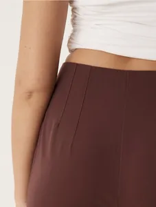 Close-up detail showing the waistline and fabric texture of high-waisted brown trousers