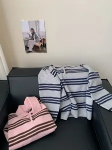 Vue détaillée de deux pulls en maille à rayures et col polo sur un canapé en cuir noir.