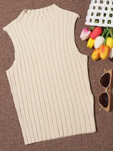 Detail view of cream ribbed knit sleeveless top with summer props on brown background.