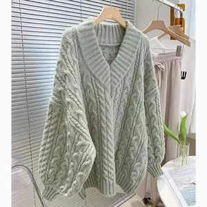 Dettaglio di un maglione a trecce verde salvia con scollo a V spesso e texture
