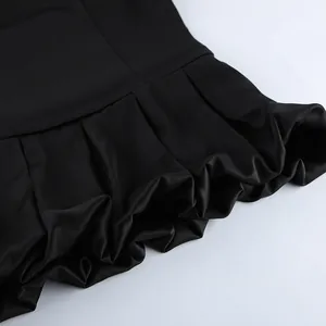 Close-up detail shot showing the elegant pleated ruffled hem of a black satin camisole top.