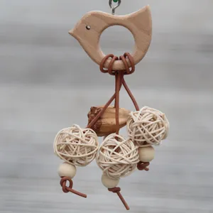 Vue détaillée d'un jouet à mâcher pour perroquet avec base en bois et balles de rotin tressées.