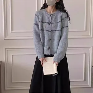Detalle de un cárdigan de punto gris con botones de cuerno y bordado floral