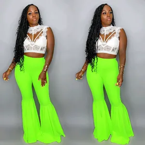 Modelo con pantalones campana verde neón con detalle elegante de dobladillo volantes.