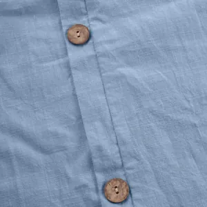 Dettaglio macro del tessuto in cotone lino blu e bottoni in legno naturale su top casual da donna
