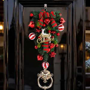 Feestelijke kerstguirlande met wit rendier en rode ornamenten op een zwarte voordeur
