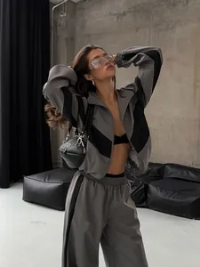 Model wearing trendy grey and black color-block tracksuit in a modern industrial studio