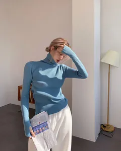 Women's blue turtleneck ribbed knit sweater shown in an elegant indoor lifestyle setting