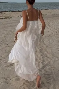 Detailed back view of a flowy white backless maxi sundress on a sunny beach vacation
