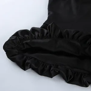 Close-up detail of the ruffled hem and glossy texture of a black satin sleeveless camisole top