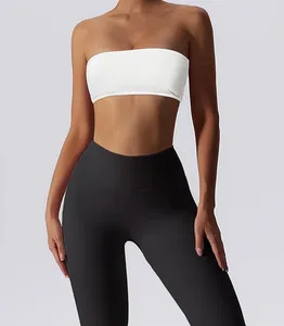 Close-up detail of a white strapless bandeau sports bra and black leggings on a model.