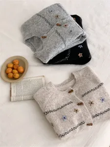 Detalle de cárdigan de punto bordado con flores y botones de cuerno de estilo clásico