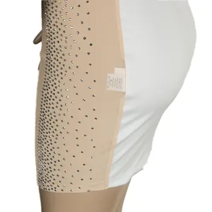 Close-up detail of silver hot-drill rhinestones on nude mesh panel of a white slim-fit dress