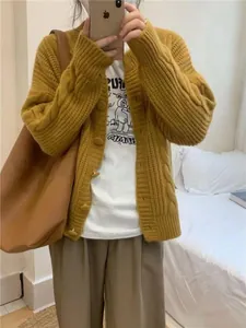 Close-up of vintage yellow cable knit cardigan worn over white graphic t-shirt