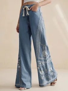 Close-up of bohemian high-waist wide-leg jeans with intricate white floral embroidery