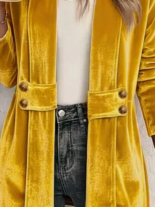 Dettaglio ravvicinato di un cardigan in velluto dorato da donna con doppi bottoni