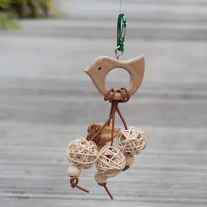 Détail de jouet pour oiseaux avec boules de rotin, forme d'oiseau en bois et graines de fruits