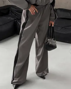 Close-up detail of women's gray wide-leg casual tracksuit pants with black side stripes