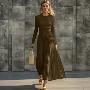 Elegante vestido largo de punto plisado de manga larga verde oliva contra pared