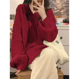Dettaglio di un pesante maglione rosso con scollo a V a trecce, vestibilità ampia per l'inverno.