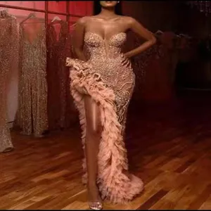 Détail d'une robe de soirée glamour à paillettes or rose avec une fente haute à volants.