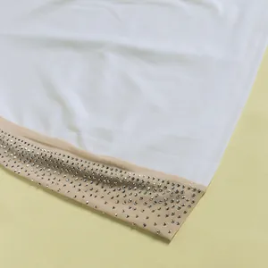 Detailed close-up showing the intricate rhinestone embellishments on a white dress hemline.