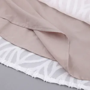 Detailansicht des weißen Jacquard-Stoffs und des hellbraunen Futters am Kleidersaum.