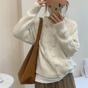 Close-up of an elegant white cable-knit crew neck sweater in relaxed fit style