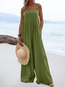 Mujer con un mono sin mangas verde oliva de pierna ancha en una playa de arena.