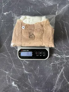 Close-up view of a brown plush dog harness vest being weighed on a digital scale for accuracy