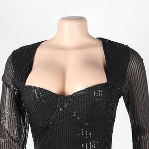 Close-up of black sequined party dress with heart-shaped neckline and mesh sleeves.