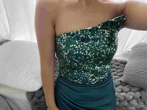 Detailansicht von schimmernden smaragdgrünen Pailletten auf einem eleganten Abendkleid