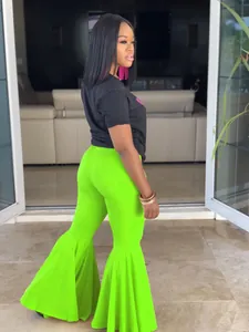 Detalle de pantalones acampanados verde neón con bajos de volantes en una modelo.