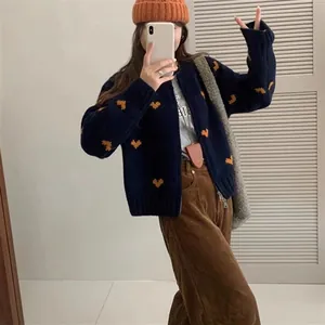 Vista lifestyle di un cardigan in maglia blu scuro con cuori e pantaloni di velluto