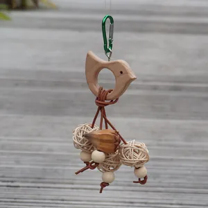 Détail d'un jouet naturel pour oiseaux en bois avec des balles de rotin pour cage.