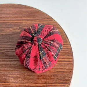 Detailed top view of a red and black plaid pet newsboy hat on a wooden tray