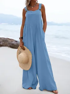 Detalle de un mono azul sin mangas de pierna ancha y botones marrones en la playa