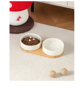 Vista dettagliata della doppia ciotola per animali in ceramica bianca con base in bambù naturale