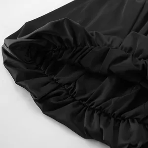 Gros plan sur le tissu en satin et l'ourlet élastique à volants du haut bustier noir.