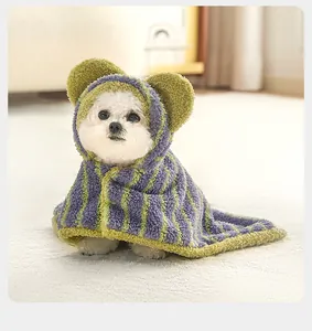 Close-up of a puppy wearing a purple and green striped hooded pet cloak with bear ears