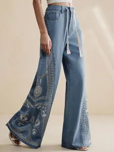 Close-up of bohemian wide-leg jeans with white floral embroidery and drawstring waist