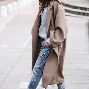 Side view of a long oversized camel wool coat for women in an urban street setting