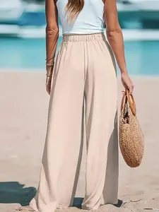 Detailed back view of women's comfortable beige wide-leg polyester casual pants on beach